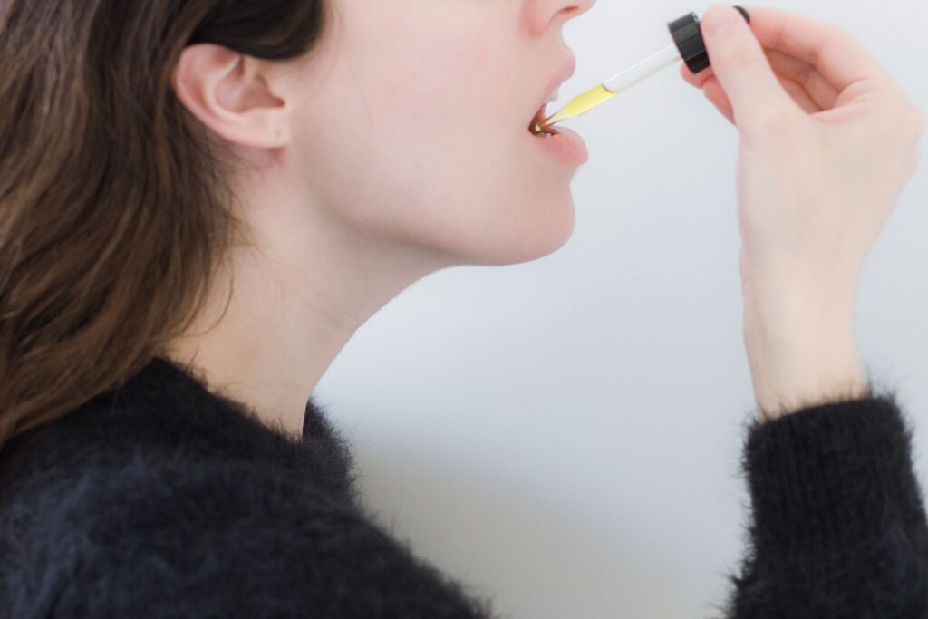 woman taking cbd tincture under tounge