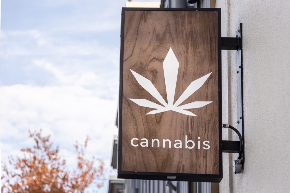A cannabis dispensary sign with a large marijuana leaf on it