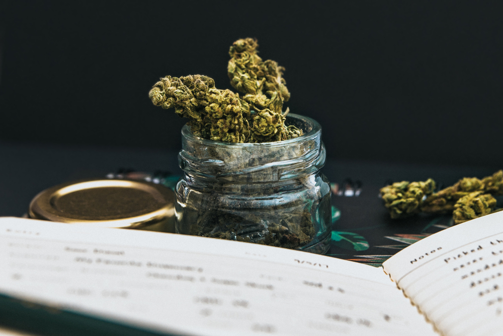 Medical marijuana buds in a glass jar with a weed journal